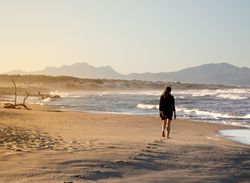 Young woman walking on shore near water
