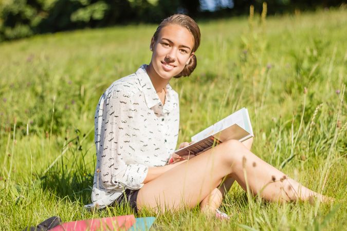 young student reading a book in the park