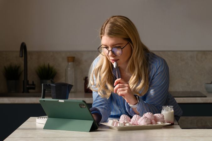 Woman working on tablet in kitchen with breakfast