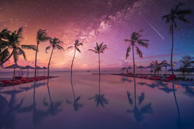 Beautiful night sky with silhouette of palm trees by the pool