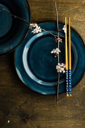 Top view of table setting with chop sticks on ceramic navy plate and cherry blossom branch