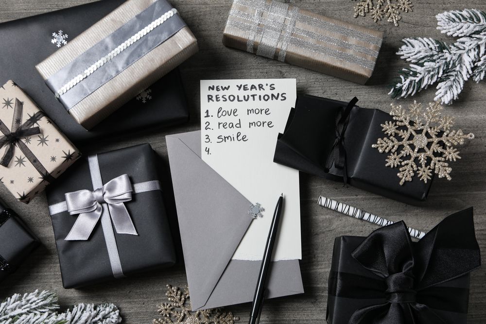 Paper with list and gift boxes on gray background, top view