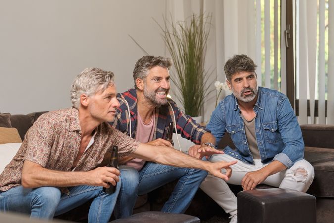 Positive men drinking beer in living room at home