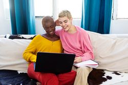 Best friends with a laptop resting on couch at home