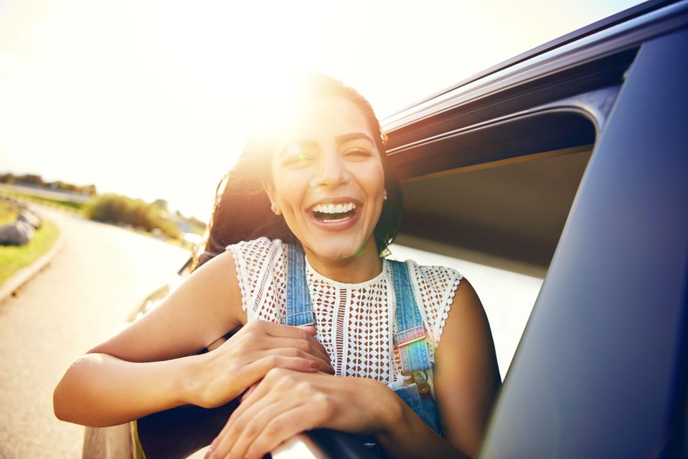 Happy woman half outside of car window