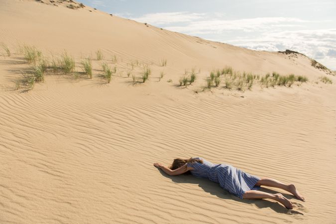 Young woman lying down on sand dune