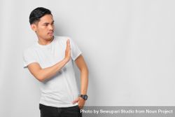 Asian male in grey studio gesturing “no” to the side with copy space 49K3W0