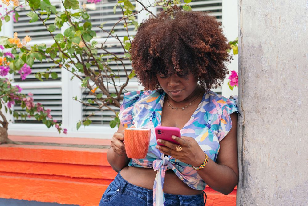 woman enjoying a coffee and looking at her cell phone on the street.