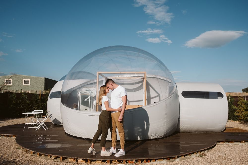 Affectionate couple kissing near bubble hotel