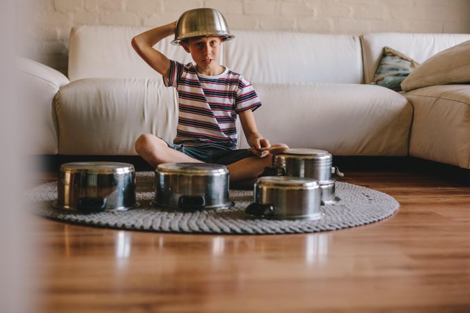 Boy playing music with cooking pots at home