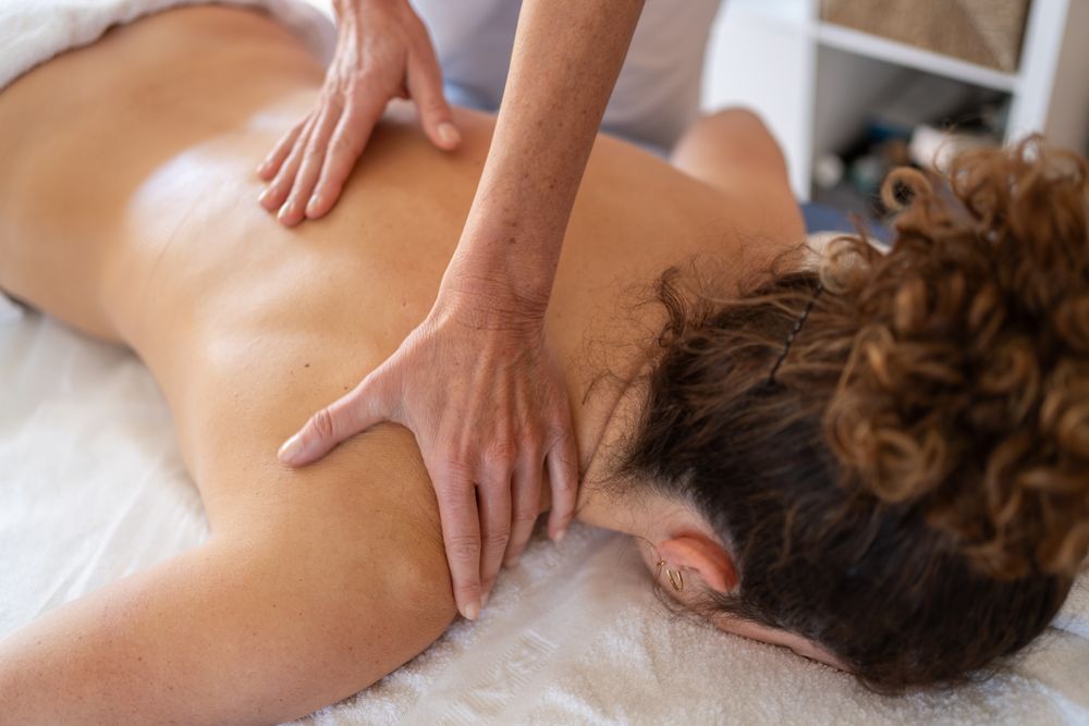 Crop masseuse kneading back of client in hospital room