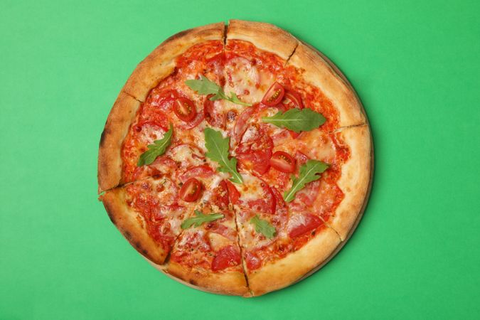 Tasty pizza with tomato on green background