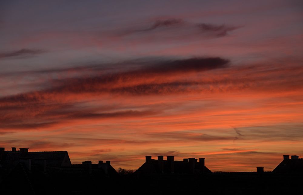 Bright orange and red clouds over homes