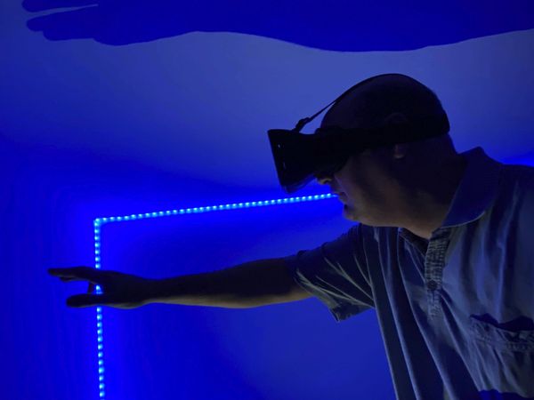 Man wearing virtual headset and standing near blue led light
