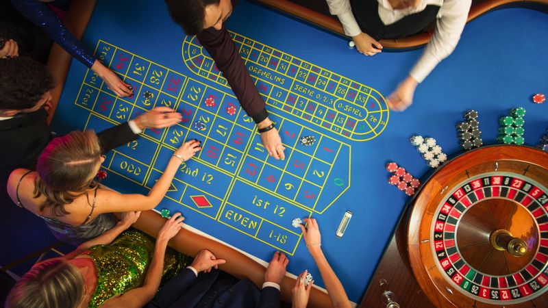 Top Down View Of Successful Men and Women Partying in a Luxurious Casino. Young People Gambling at a Roulette Table, Putting High Stakes Bets. Entertainment Industry and Glamorous Lifestyle Concept.