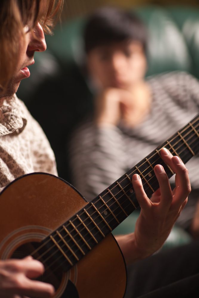Young Musician Plays His Acoustic Guitar as Friend Listens