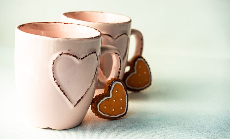 St. Valentine's day card concept with two pink mugs on counter with heart cookies