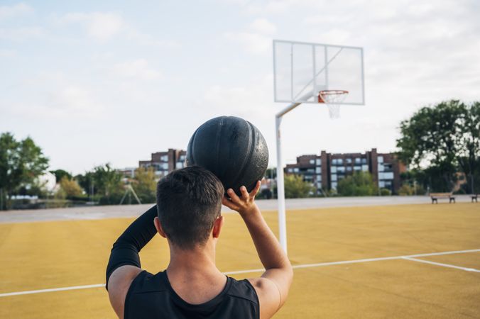 Young man playing on basketball court outdoor.