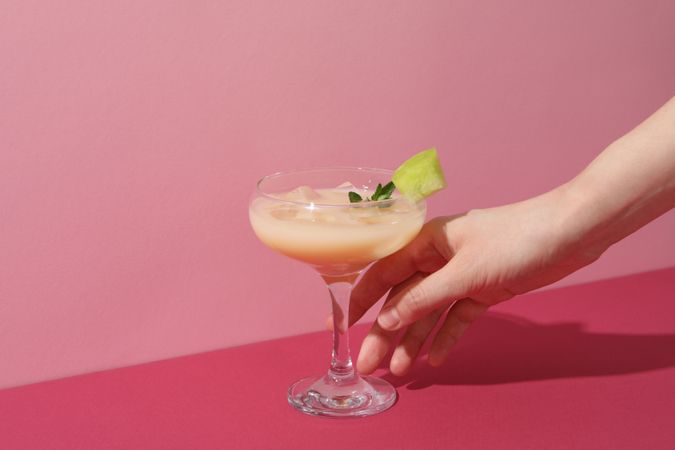 A glass of fresh melon juice on a pink background