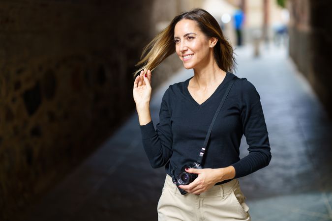 Woman with camera playing with hair in arch