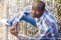 Male in plaid shirt sitting on stairs and looking up 0LwYXb