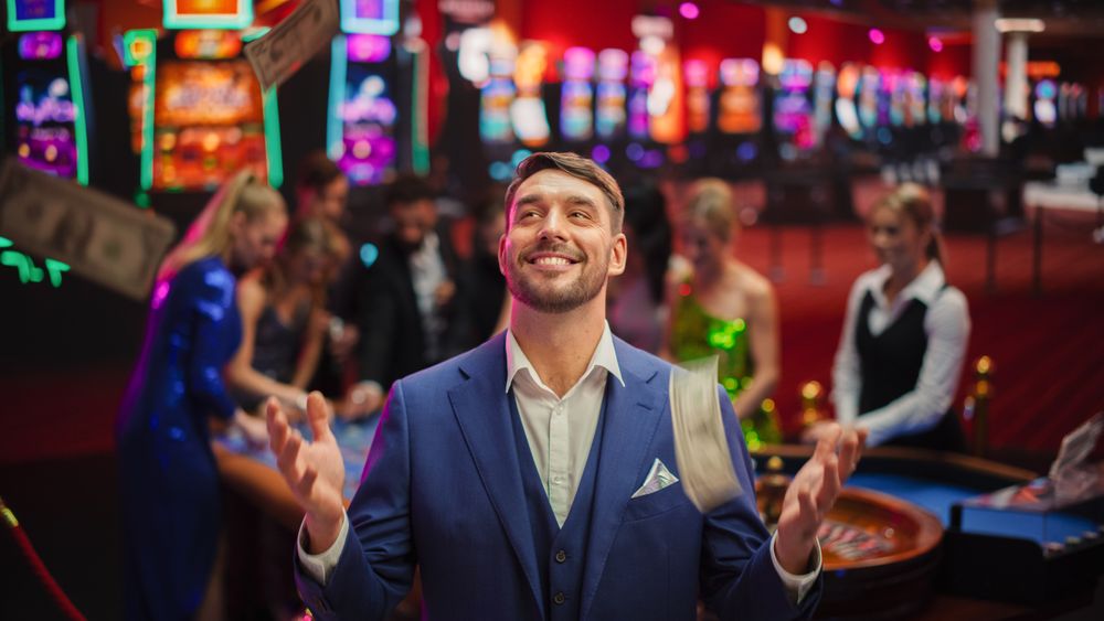 Happy Man in a Suit Standing in the Middle of a Modern Casino, Extending Arms,