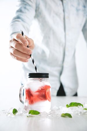 Man putting straw into strawberry infused water