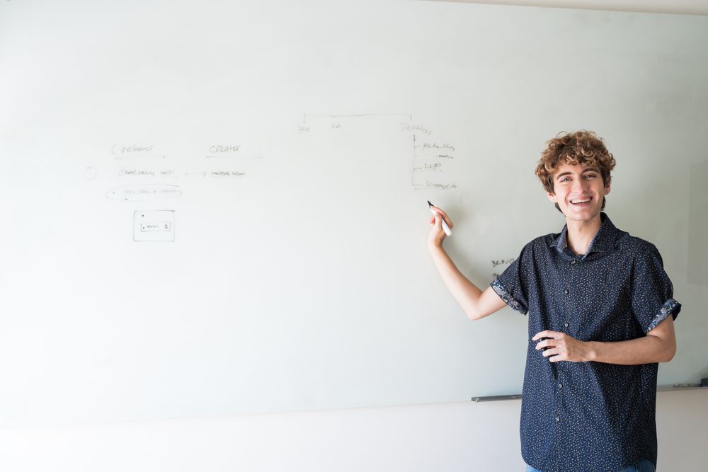 Nonbinary person at a dry erase board with marker