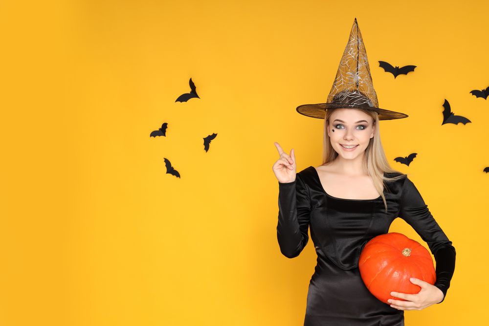 Concept of Halloween, young woman on yellow background