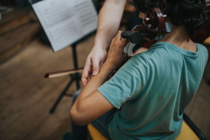Teacher helping student adjust arm to play instrument