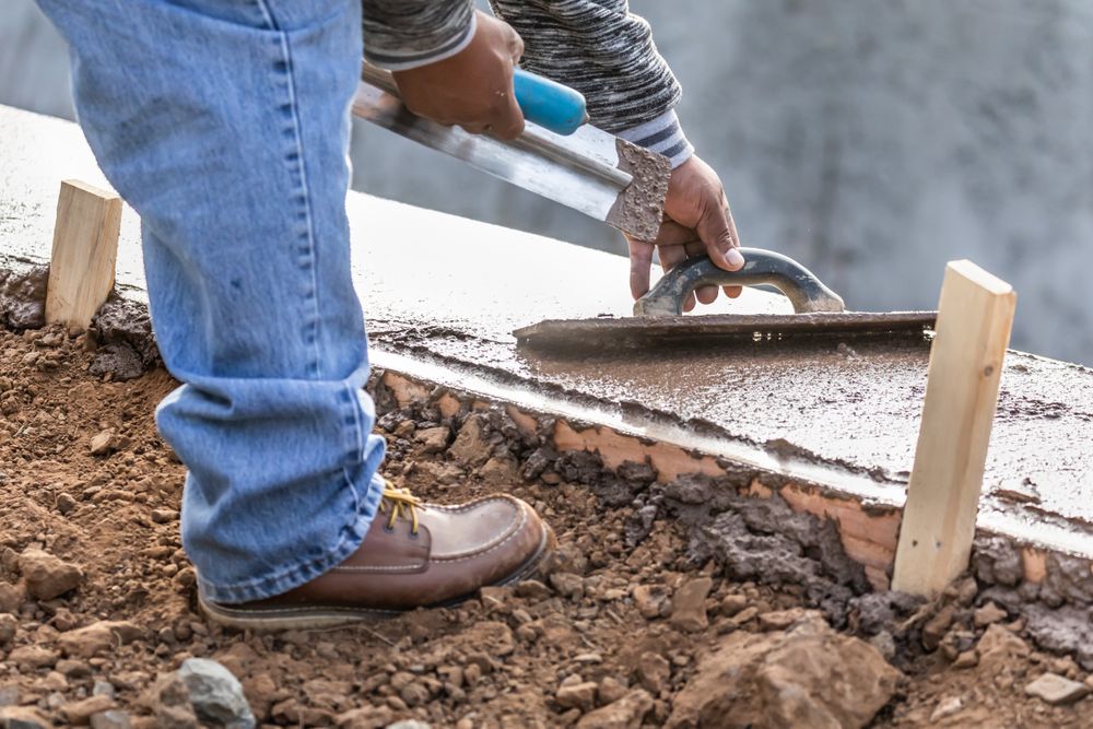 Construction Worker Using Wood Trowel On Wet Cement Forming Coping Around New Pool