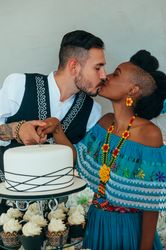 Bride and groom share a kiss while cutting the wedding cake