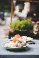 Spring rolls and dim sum pictured on table, side view, with chop sticks and dipping sauce