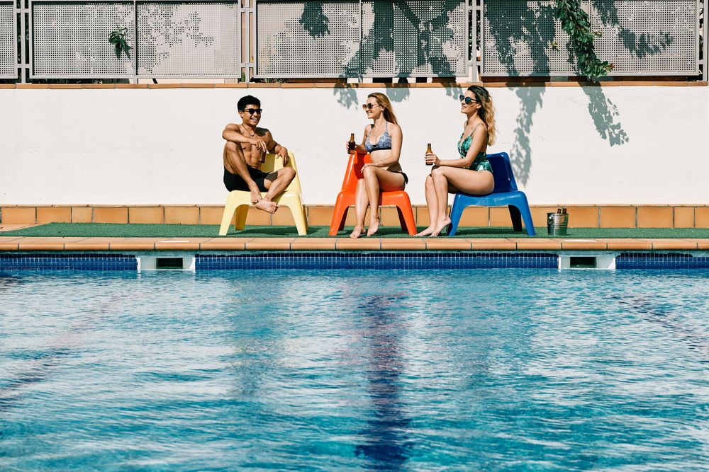 two young women looking at a handsome man by the pool