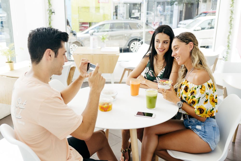 Man taking picture of friends in cafe