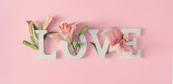 “Love” written on pink background with spring flowers