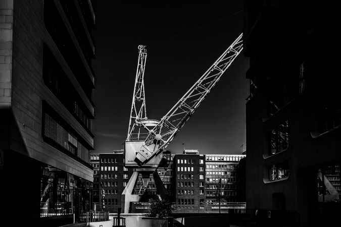 Grayscale photo of crane near building