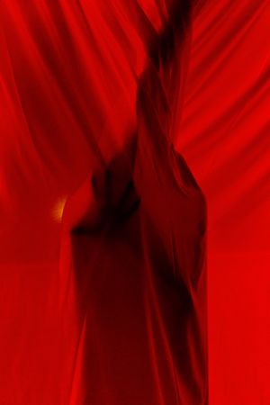Faceless person hiding behind curtains at night time