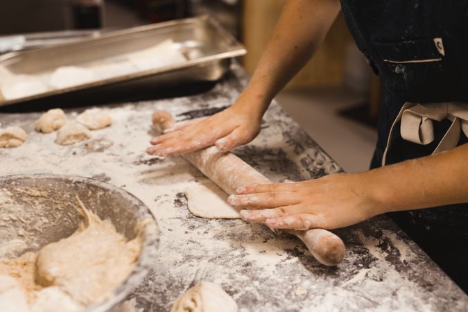 Baker rolling out dough in kitchen