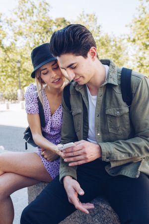Happy young couple using phone in park