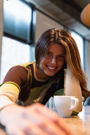 Cheerful woman with cup of coffee in cafe
