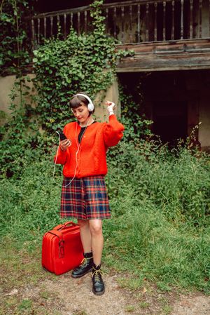 Woman in headphones with suitcase choosing music