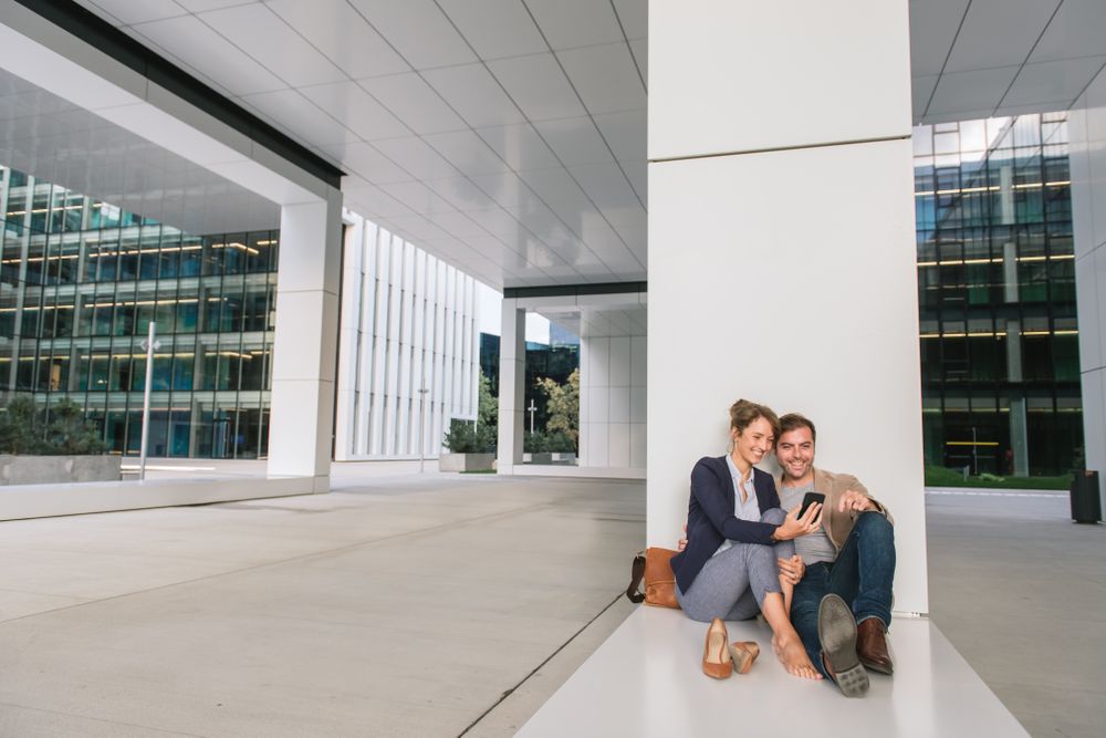 Businesspeople hugging and using smartphone on street