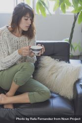 Curious female on cozy sofa with cup of tea, copy space 5wNpL0