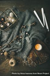 Festive decorations, candles, garland, yarn and scissors arranged around grey woolen sweater begq65