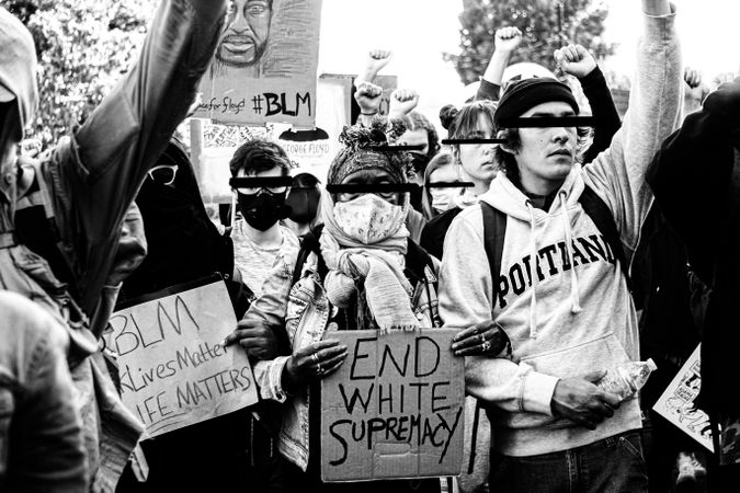 Grayscale photo of people with face masks holding banners at " Black Lives Matter" protest 
