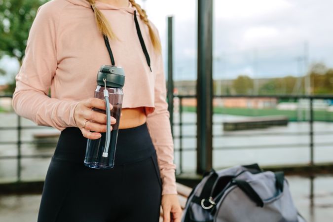 Young sportswoman with water bottle and gym bag