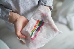 Faceless boy with wet wipe painted with rainbow