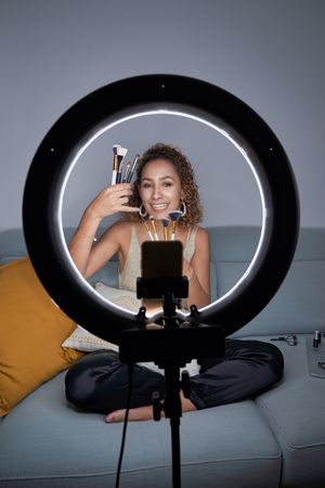 Smiling woman showing set of professional brushes while recordin