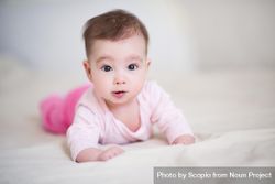 Baby in pink pajama laying forward on textile 5aweKb